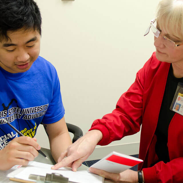 Student signing papers with Health services staff